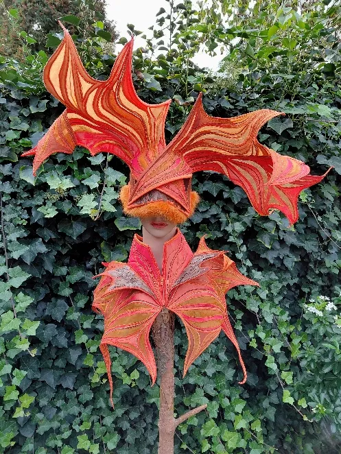 Oranje en rode organische vormen op een vertakte houten sculptuur in de tuin